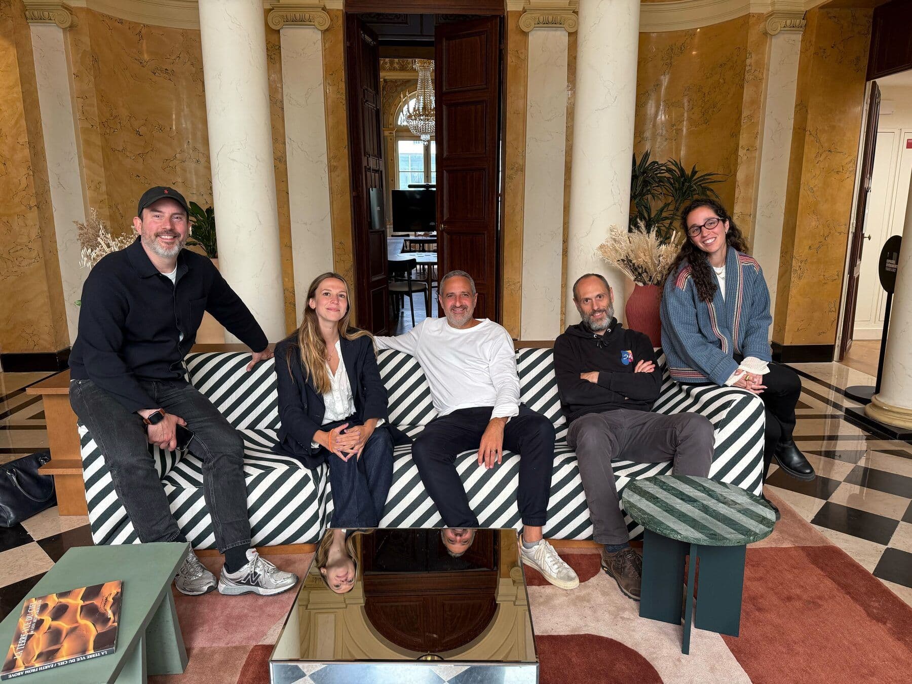 The 26lights team in a lounge, five people sitting on a striped sofa